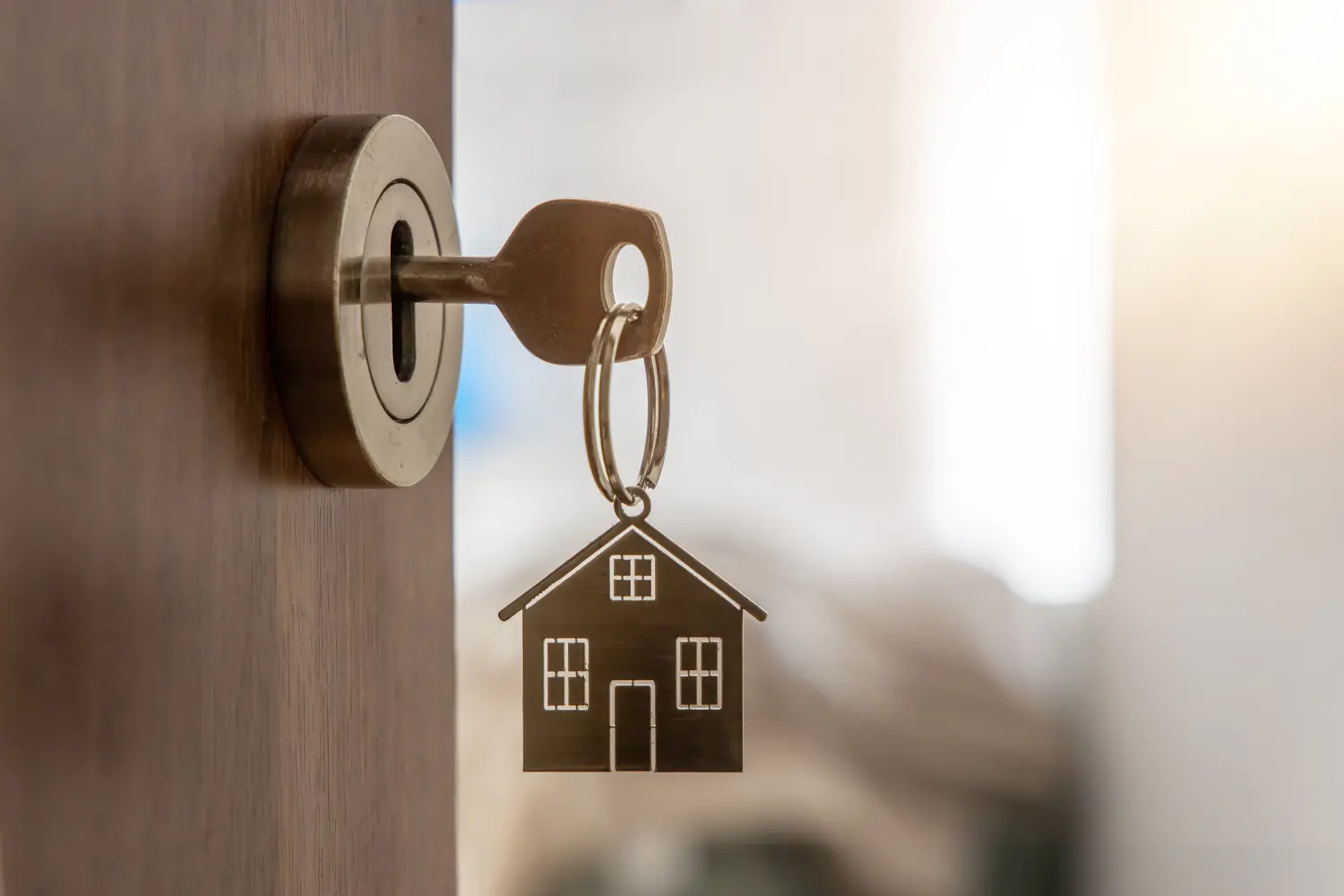 Offene Tür zu einem neuen Zuhause mit Schlüssel und Schlüsselanhänger in Hausform. Hypotheken, Investitionen, Immobilien, Grundstücke und neues Zuhause – Konzept