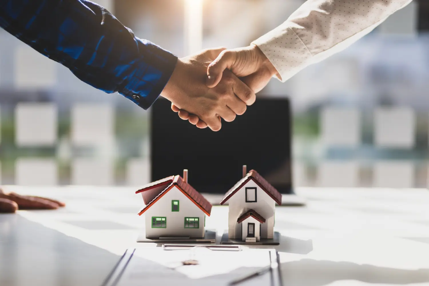 Immobilienmakler geben sich nach Vertragsunterzeichnung die Hand.
