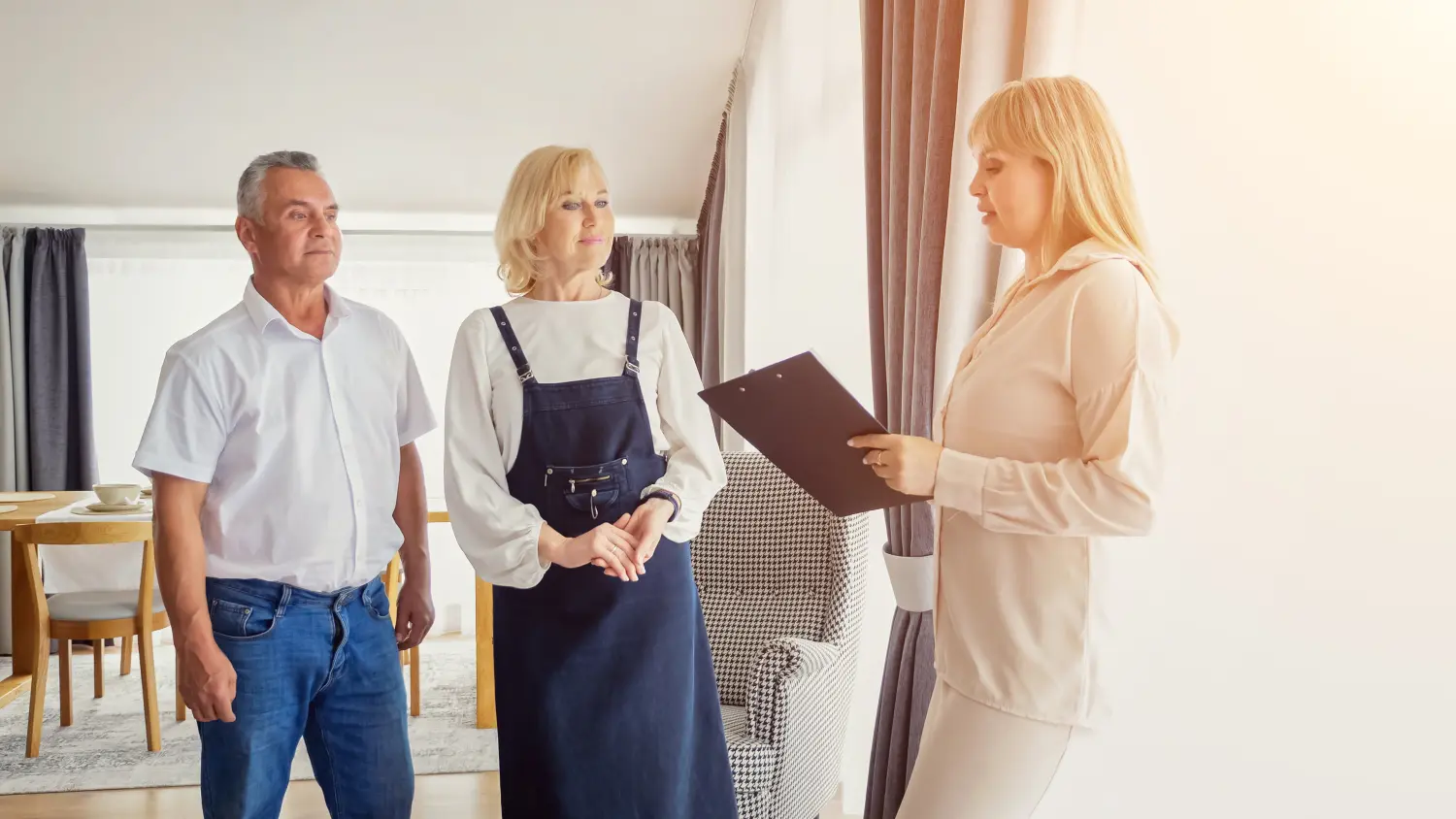 Professioneller Immobilienmakler zeigt erwachsener Tochter und älterem Vater die Inneneinrichtung eines Ferienhauses.